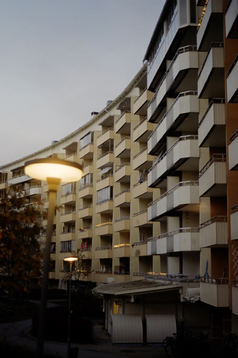 Curved apartment building at dusk with glowing street lamp